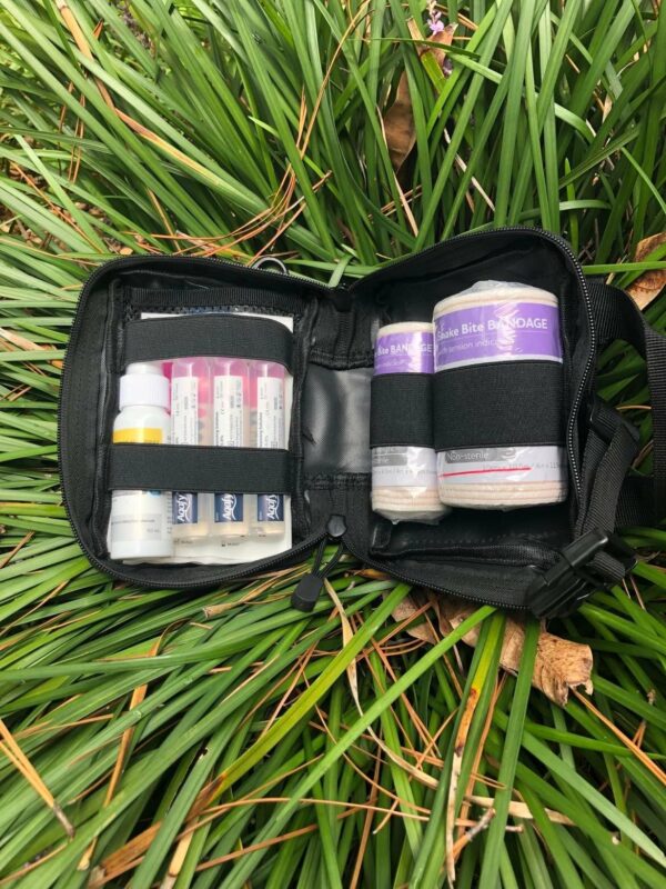 A bag filled with medical supplies laying in the grass.